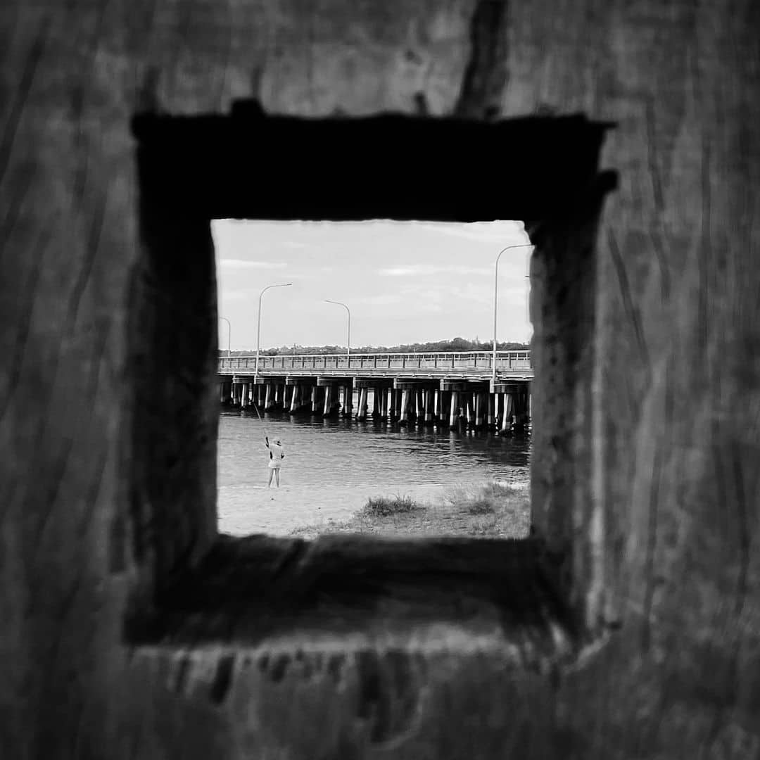 a square hole in a wooden fence overlooking the sea