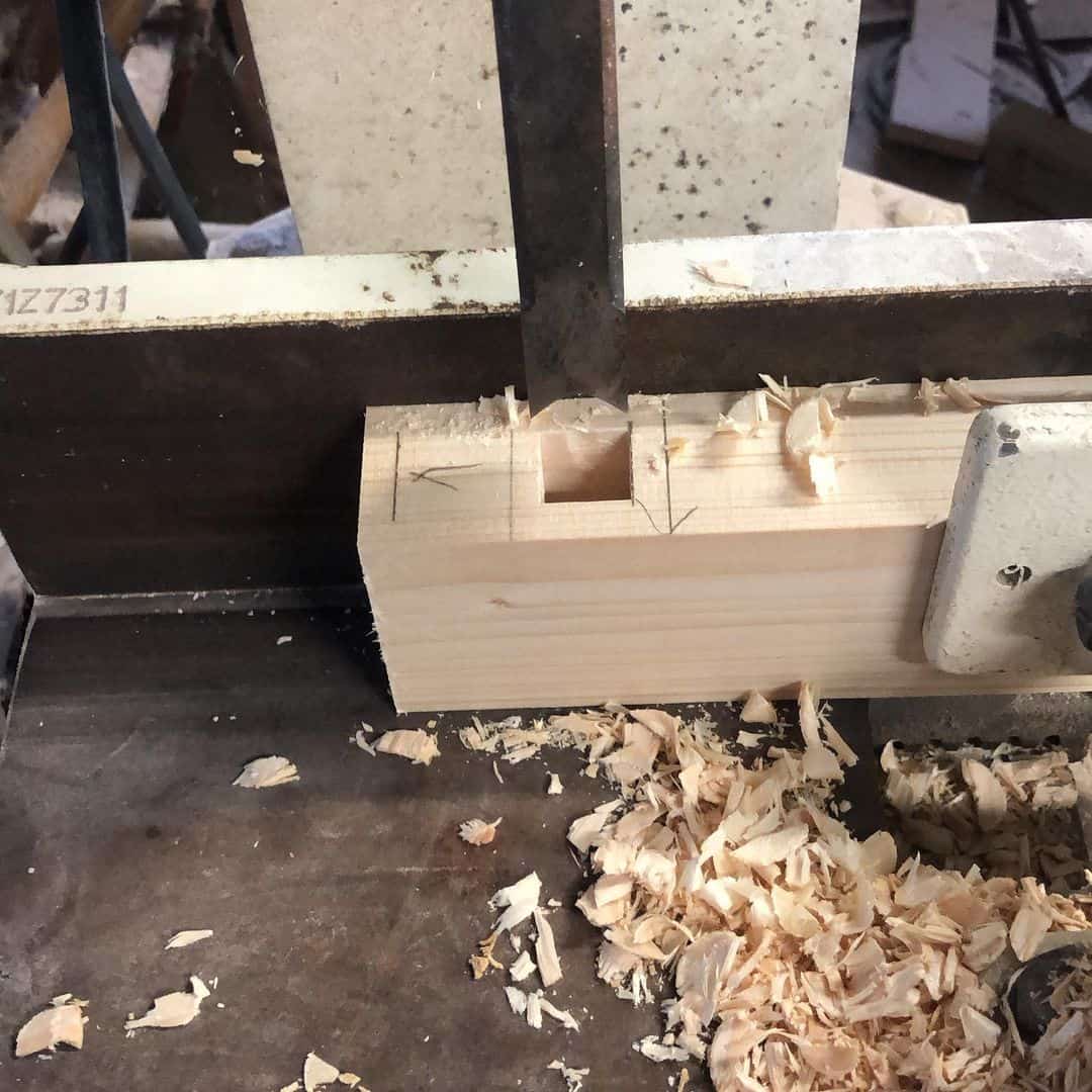 the process of drilling a square hole in a wooden bar