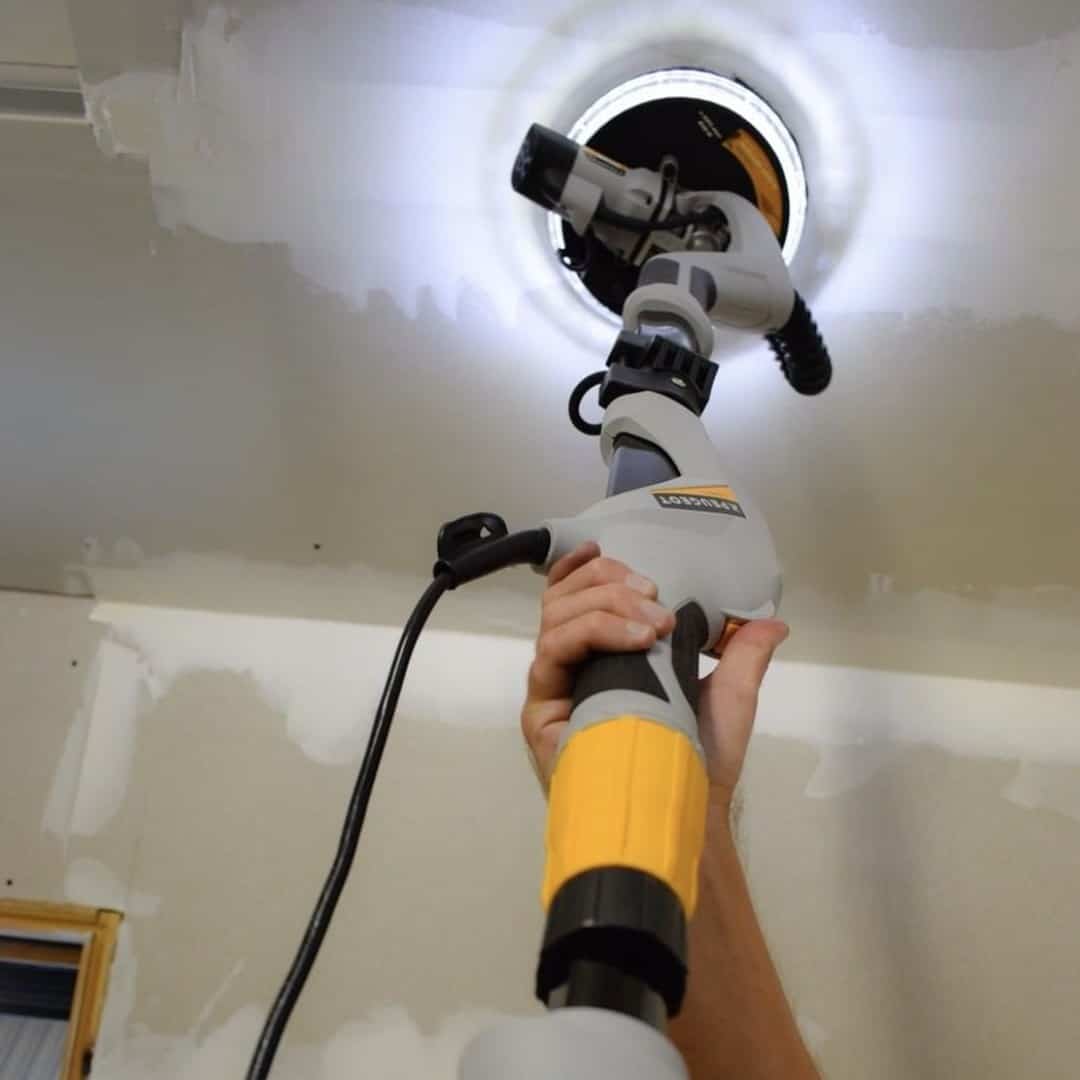 The drywall sander with light grinds the ceiling
