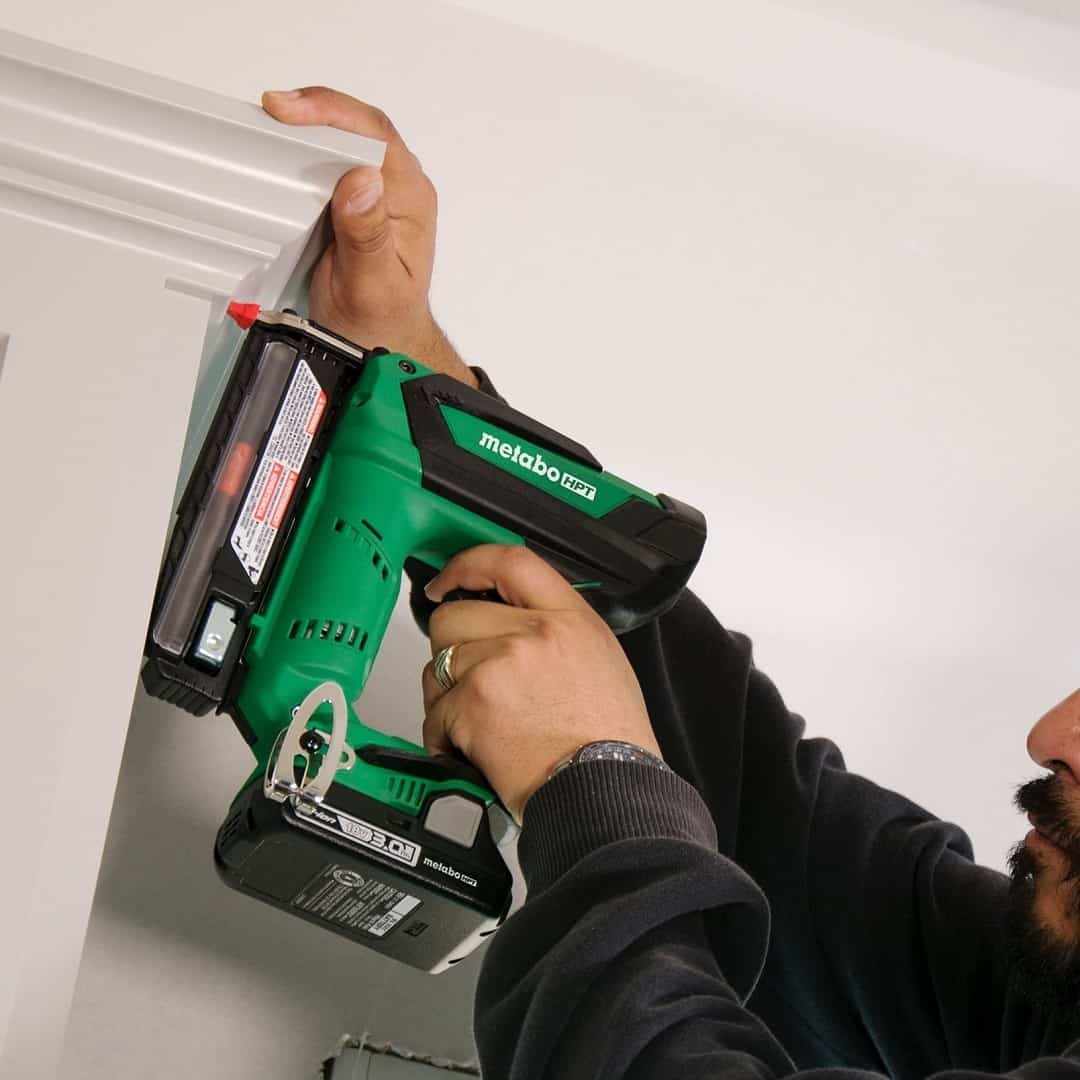 A man works with a green pin nailer