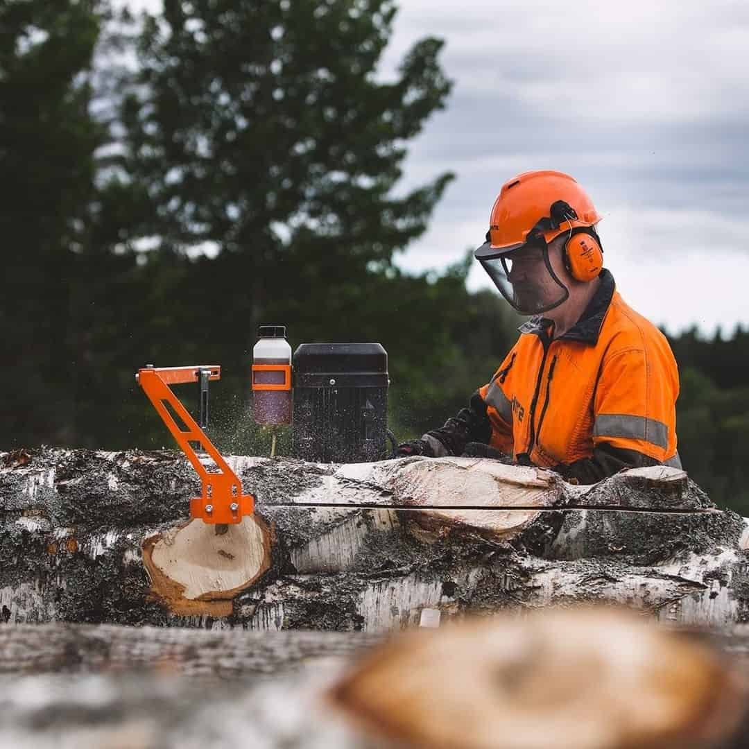 Lumberjack in protective mask milling a log