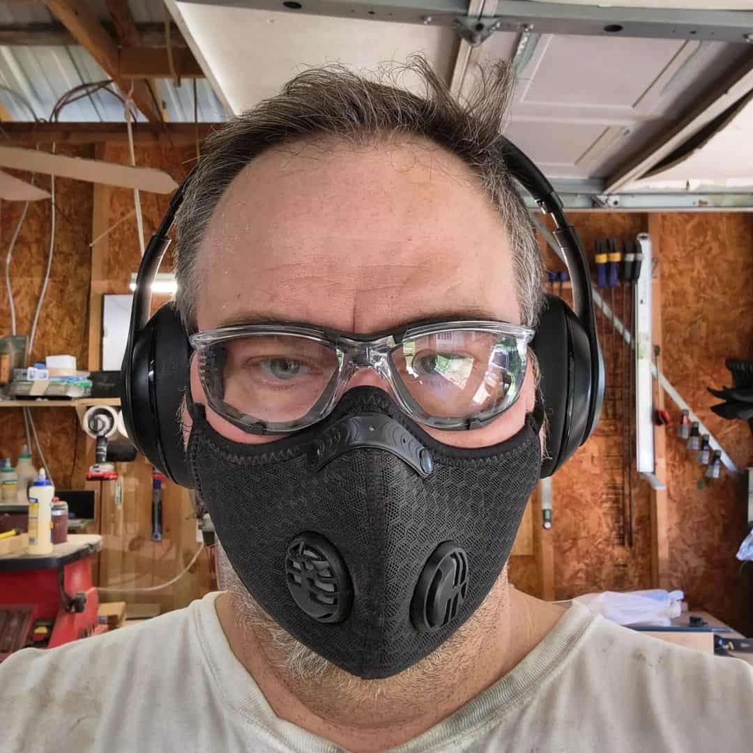 man wearing goggles respirator and headphones