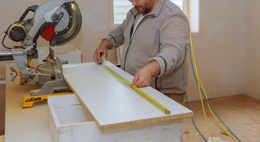 man measuring laminate flooring with a tape measure